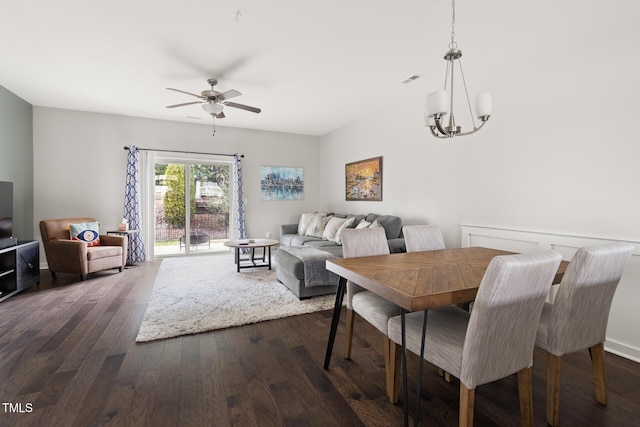 dining space with dark hardwood / wood-style flooring and ceiling fan with notable chandelier