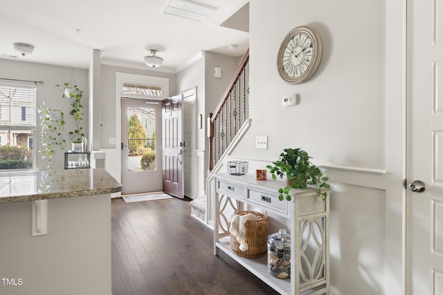 foyer with ornamental molding and dark hardwood / wood-style floors