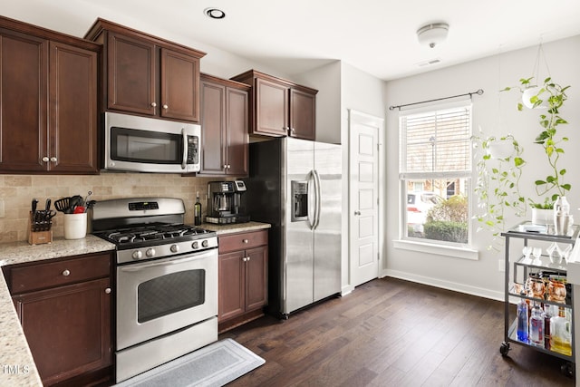 kitchen featuring tasteful backsplash, light stone countertops, dark hardwood / wood-style flooring, and stainless steel appliances