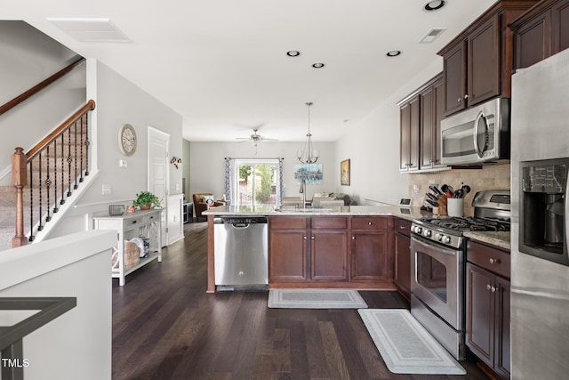 kitchen with pendant lighting, sink, stainless steel appliances, dark hardwood / wood-style floors, and kitchen peninsula