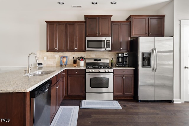 kitchen featuring sink, appliances with stainless steel finishes, dark hardwood / wood-style floors, light stone countertops, and backsplash