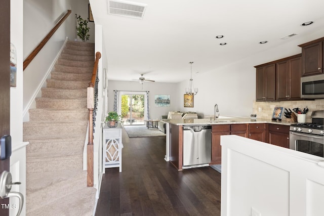 kitchen with sink, appliances with stainless steel finishes, dark brown cabinetry, dark hardwood / wood-style flooring, and decorative backsplash