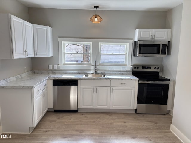 kitchen with sink, white cabinetry, hanging light fixtures, stainless steel appliances, and light stone countertops