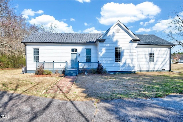 view of front facade with a front yard, roof with shingles, and a wooden deck