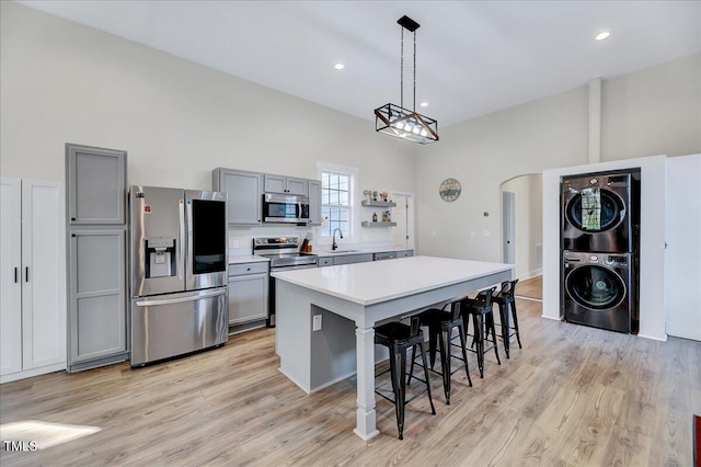 kitchen with arched walkways, stainless steel appliances, light countertops, gray cabinetry, and a sink