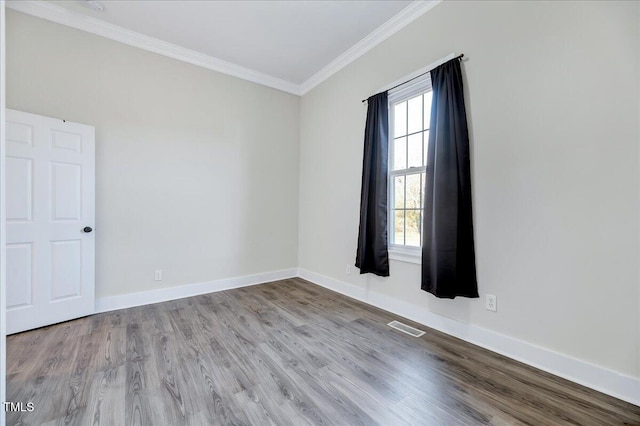 spare room featuring ornamental molding, visible vents, light wood-style flooring, and baseboards