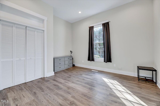 unfurnished bedroom featuring light wood-style floors, a closet, visible vents, and baseboards