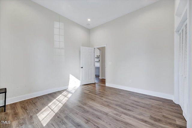 unfurnished bedroom featuring recessed lighting, wood finished floors, and baseboards