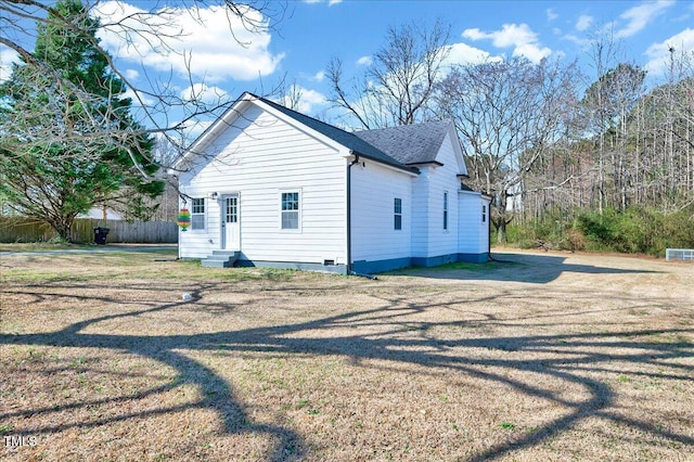 view of side of home featuring entry steps, a shingled roof, fence, and a lawn