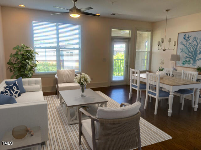 living area featuring baseboards, ceiling fan, wood finished floors, and a healthy amount of sunlight