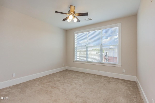 empty room featuring light colored carpet, visible vents, ceiling fan, and baseboards