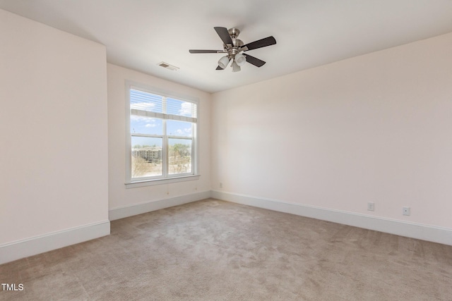 carpeted empty room with baseboards, visible vents, and a ceiling fan