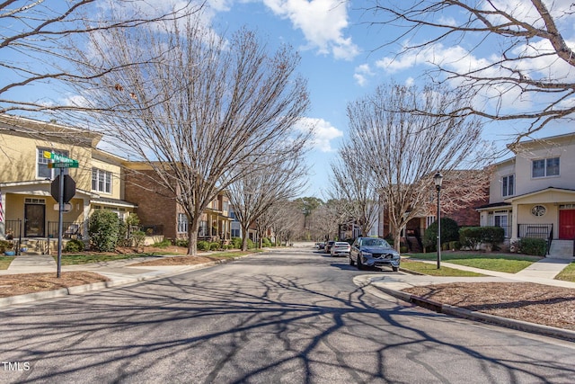 view of street featuring street lights, traffic signs, sidewalks, a residential view, and curbs