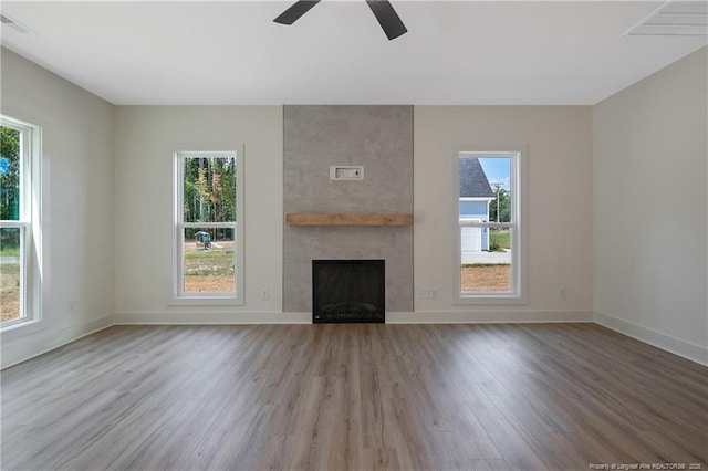 unfurnished living room featuring ceiling fan, a fireplace, and light hardwood / wood-style flooring