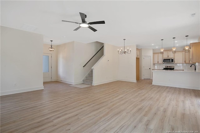 unfurnished living room with sink, ceiling fan with notable chandelier, and light hardwood / wood-style floors