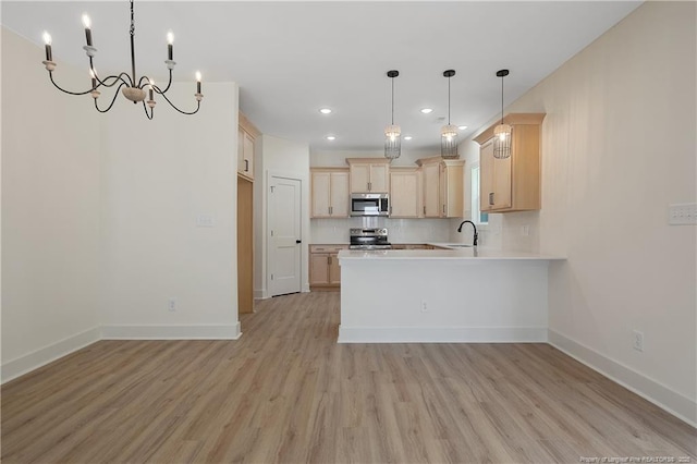 kitchen with appliances with stainless steel finishes, decorative light fixtures, backsplash, kitchen peninsula, and light brown cabinets