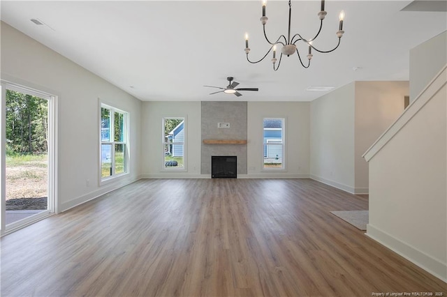 unfurnished living room featuring hardwood / wood-style floors, ceiling fan with notable chandelier, and a fireplace