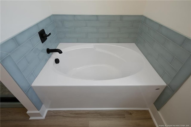 bathroom with a tub to relax in and hardwood / wood-style flooring