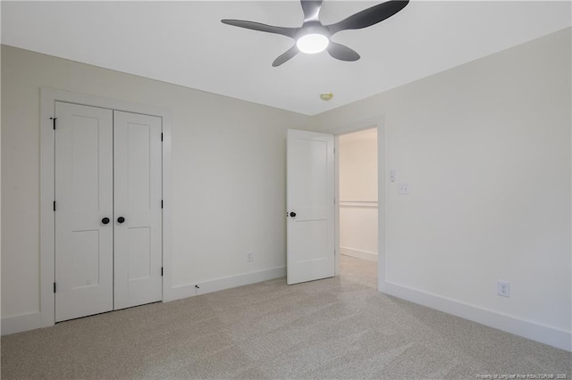 unfurnished bedroom with ceiling fan, light colored carpet, and a closet