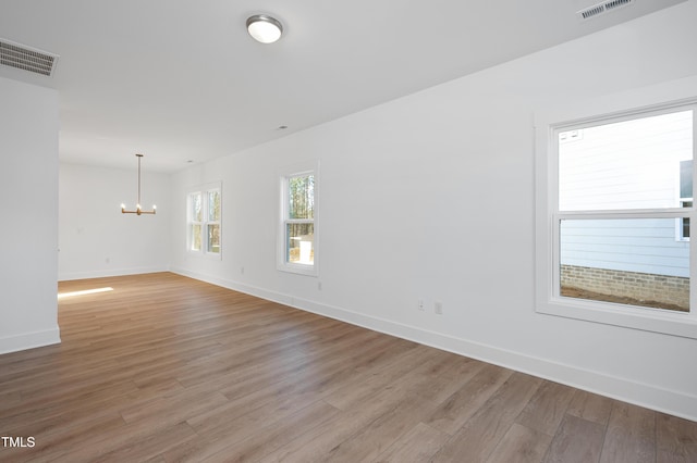 empty room featuring an inviting chandelier and wood-type flooring