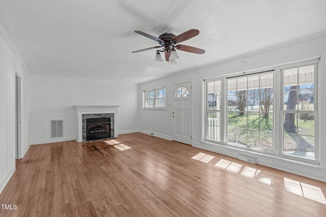 unfurnished living room featuring a premium fireplace, wood finished floors, visible vents, and crown molding