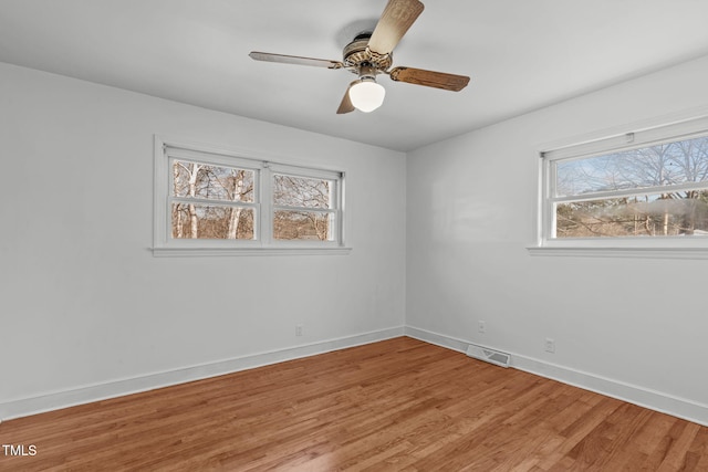 spare room with baseboards, light wood-style floors, visible vents, and a healthy amount of sunlight