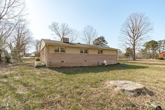 exterior space featuring crawl space, brick siding, a chimney, and a yard