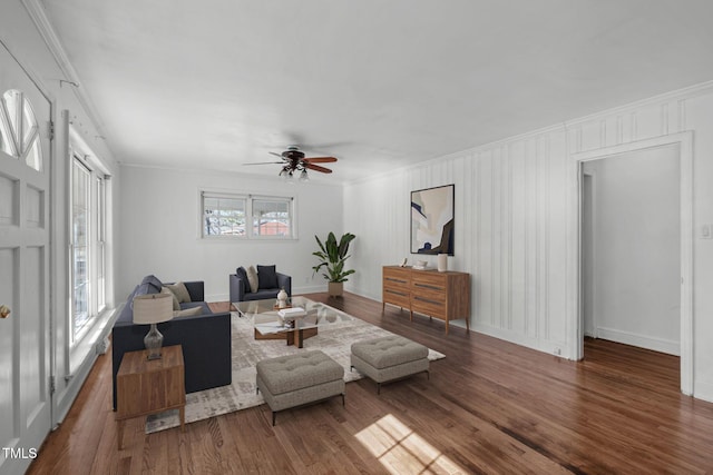 living area with ceiling fan, crown molding, baseboards, and wood finished floors