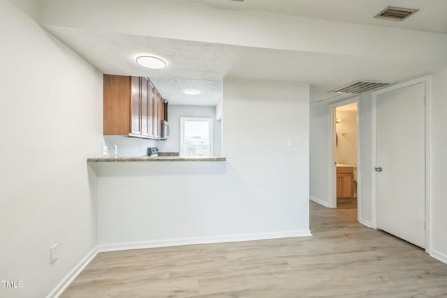 408 Cumbrian Ct, Fayetteville, NC 28314 - kitchen featuring brown cabinetry, light wood-style floors, baseboards, light countertops, and stainless steel microwave