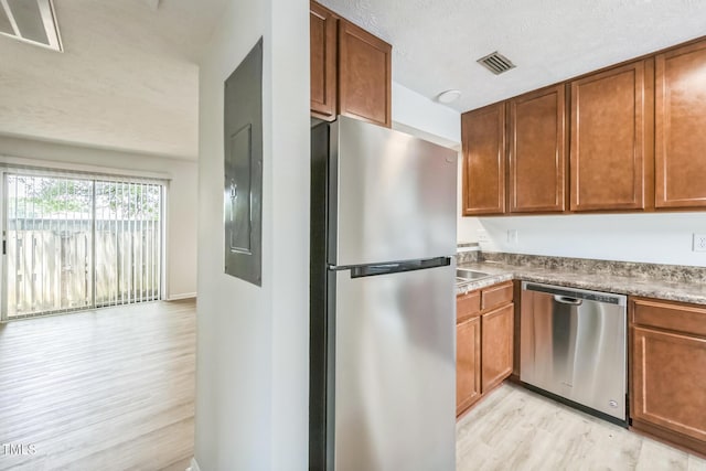 408 Cumbrian Ct, Fayetteville, NC 28314 - kitchen featuring appliances with stainless steel finishes, light wood-style flooring, a textured ceiling, and brown cabinets