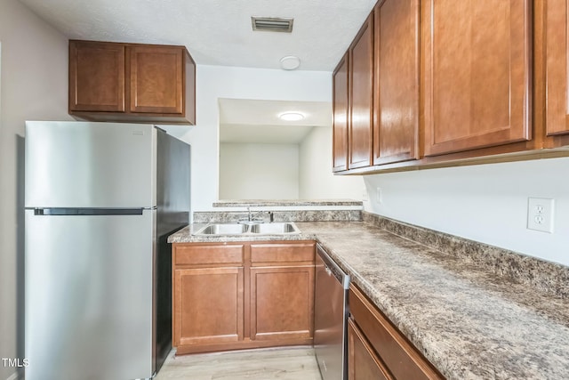 408 Cumbrian Ct, Fayetteville, NC 28314 - kitchen featuring appliances with stainless steel finishes, a sink, brown cabinets, and light wood-style floors