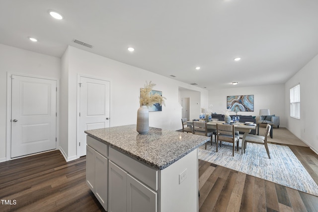 kitchen featuring light stone countertops, dark wood-style floors, recessed lighting, and a center island