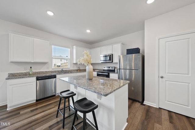 kitchen with stainless steel appliances, dark wood-style flooring, a sink, and white cabinetry