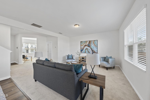 living room with carpet, baseboards, visible vents, and wood finished floors