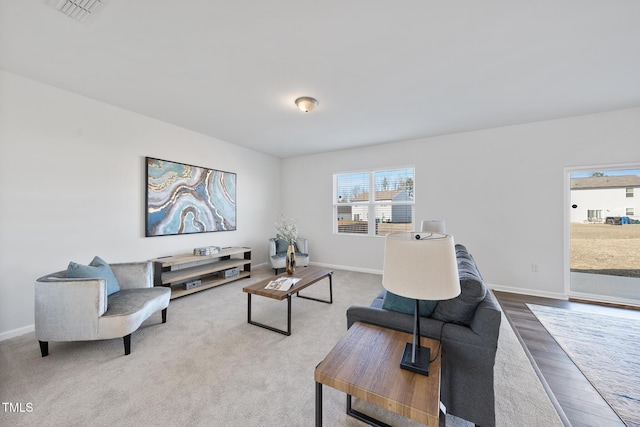 living area with baseboards, visible vents, and wood finished floors