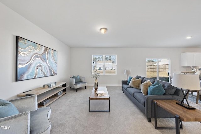 living area featuring a wealth of natural light, light colored carpet, and baseboards