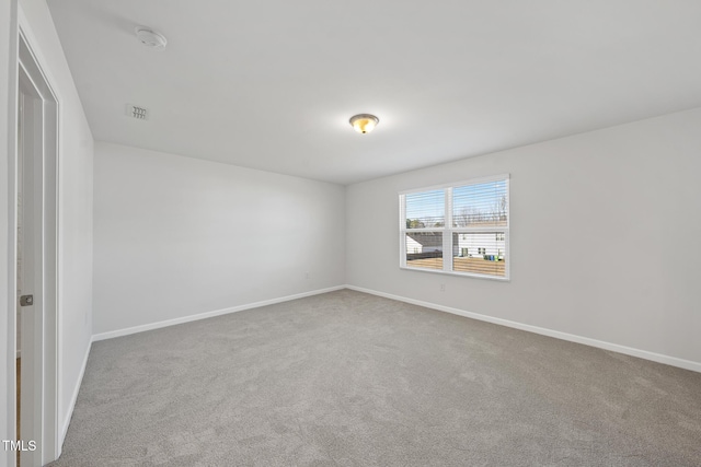 empty room featuring carpet flooring, visible vents, and baseboards