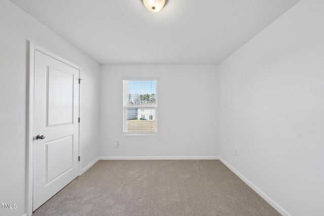 carpeted spare room featuring baseboards