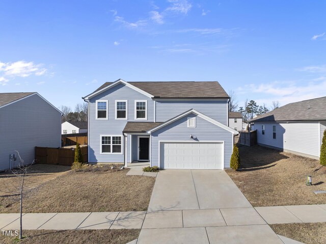 traditional-style house with a garage, concrete driveway, and fence