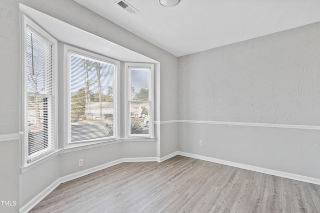 unfurnished room with wood finished floors, visible vents, and baseboards