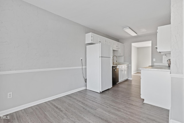 kitchen with light countertops, freestanding refrigerator, white cabinets, wood finished floors, and dishwasher