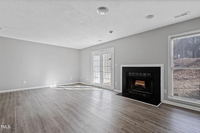 unfurnished living room featuring a fireplace, wood finished floors, visible vents, and baseboards