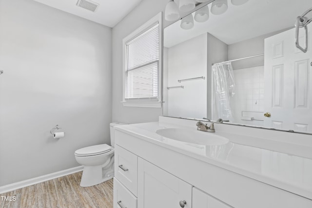 bathroom featuring toilet, wood finished floors, vanity, visible vents, and baseboards