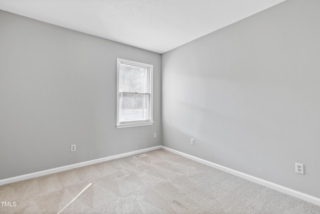 carpeted spare room with visible vents, a textured ceiling, and baseboards