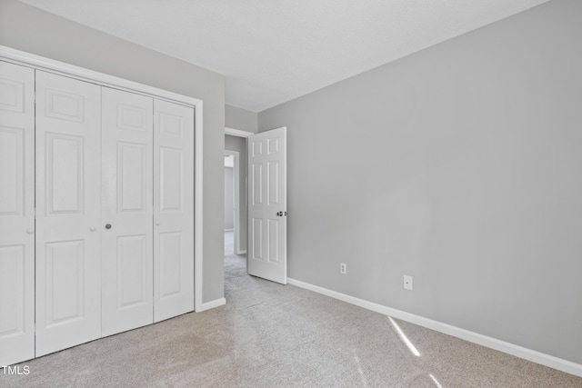 unfurnished bedroom featuring carpet, baseboards, and a closet