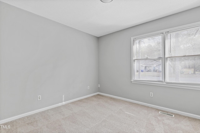 carpeted spare room with visible vents and baseboards