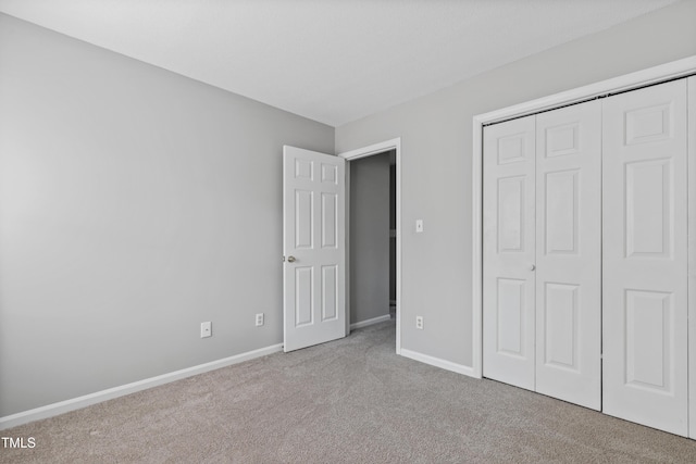 unfurnished bedroom with a closet, carpet flooring, and baseboards