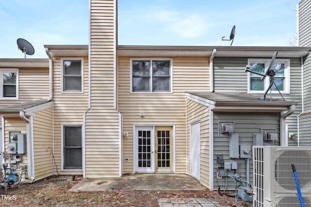 rear view of house with cooling unit, french doors, a patio, and a chimney