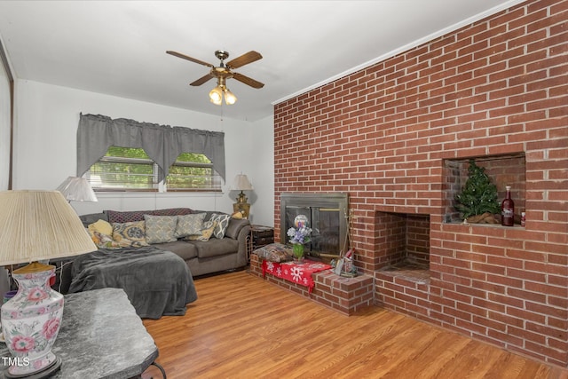 living area featuring a ceiling fan, wood finished floors, and a fireplace