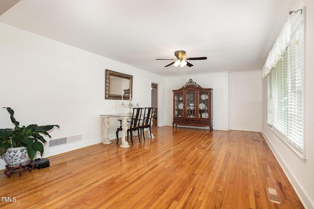 interior space featuring baseboards, visible vents, a ceiling fan, and light wood finished floors